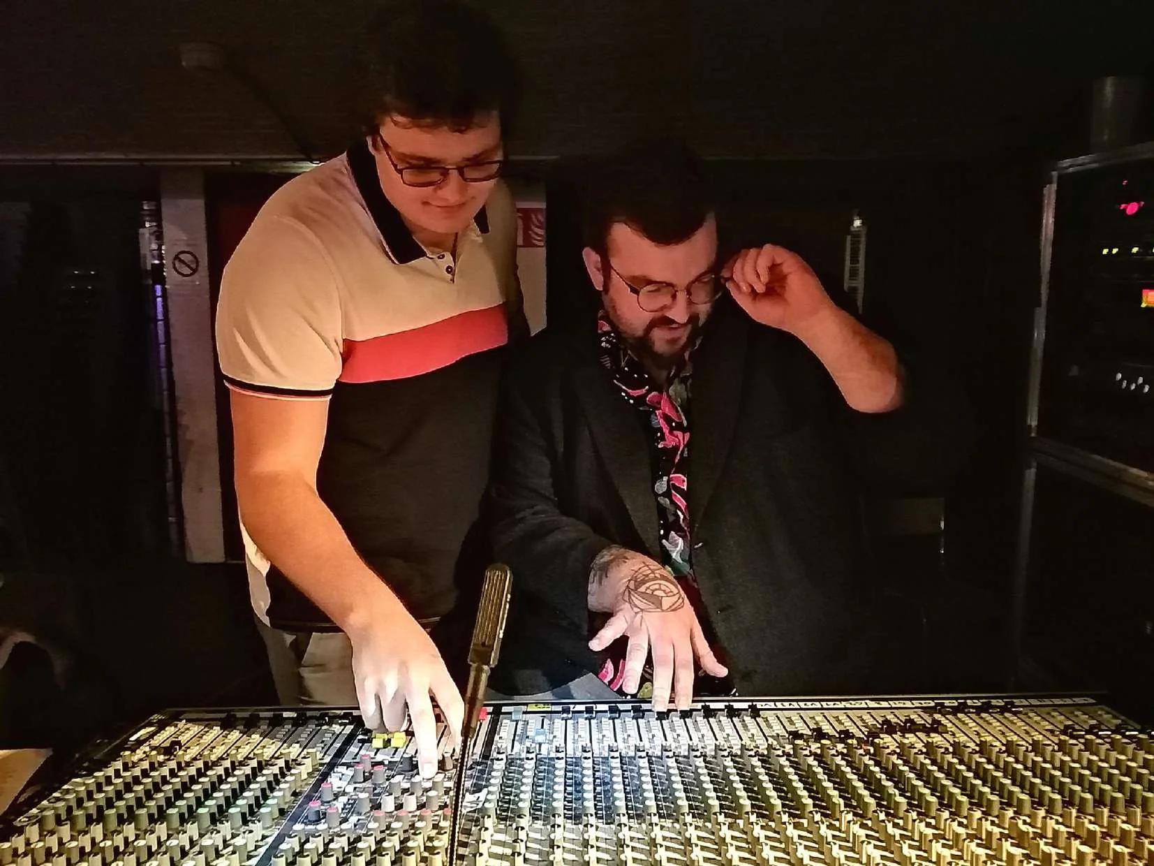 Deux personnes travaillant ensemble devant une console de mixage